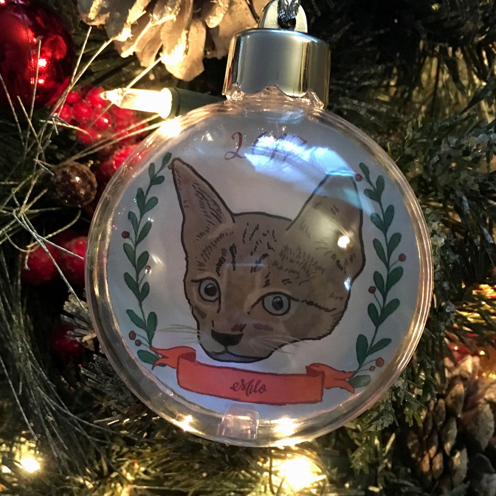 Holiday ornament with an illustrated portrait of a cat named Milo