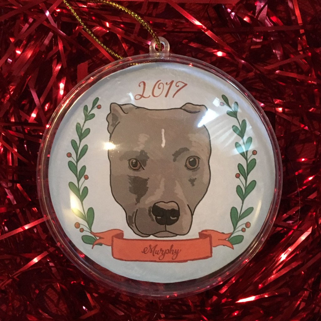 Holiday ornament with an illustrated portrait of a dog namedMurphy