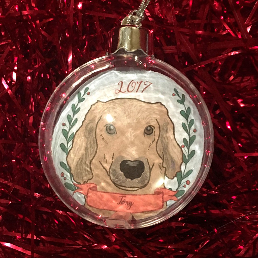 Holiday ornament with an illustrated portrait of a dog named Tony