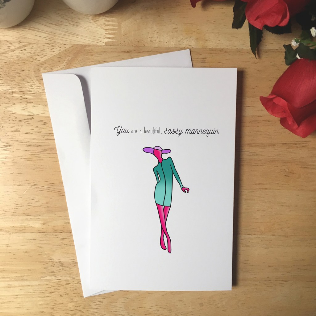 Greeting Card design with an illustrated pink mannequin wearing a purple floppy hat and green dress. The text reads You are a beautiful, sassy mannequin.
