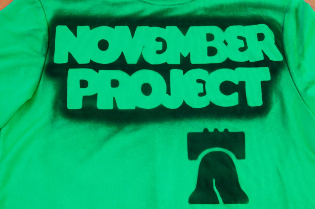 Image of a green t-shirt tagged with the November Project logo